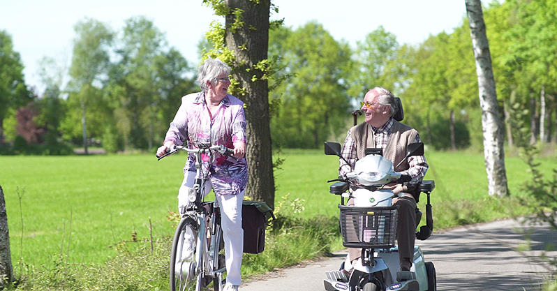man-in-scootmobiel-met-fietsende-vrouw